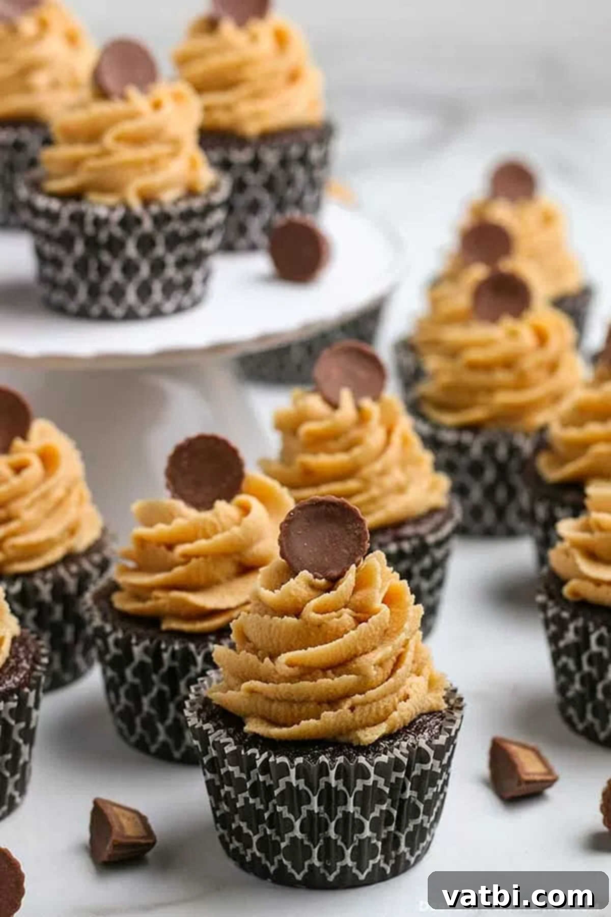 Chocolate and peanut butter fans will go crazy over Chocolate cupcakes with peanut butter frosting. Each bite is moist and delicious and so decadent. This recipe for homemade cupcakes makes baking from scratch easy. Try the best cupcakes with dark chocolate and peanut butter today. #dessertonadime #chocolatepeanutbuttercupcakes Chocolate and peanut butter cupcakes topped with Reese's Peanut Butter Cups