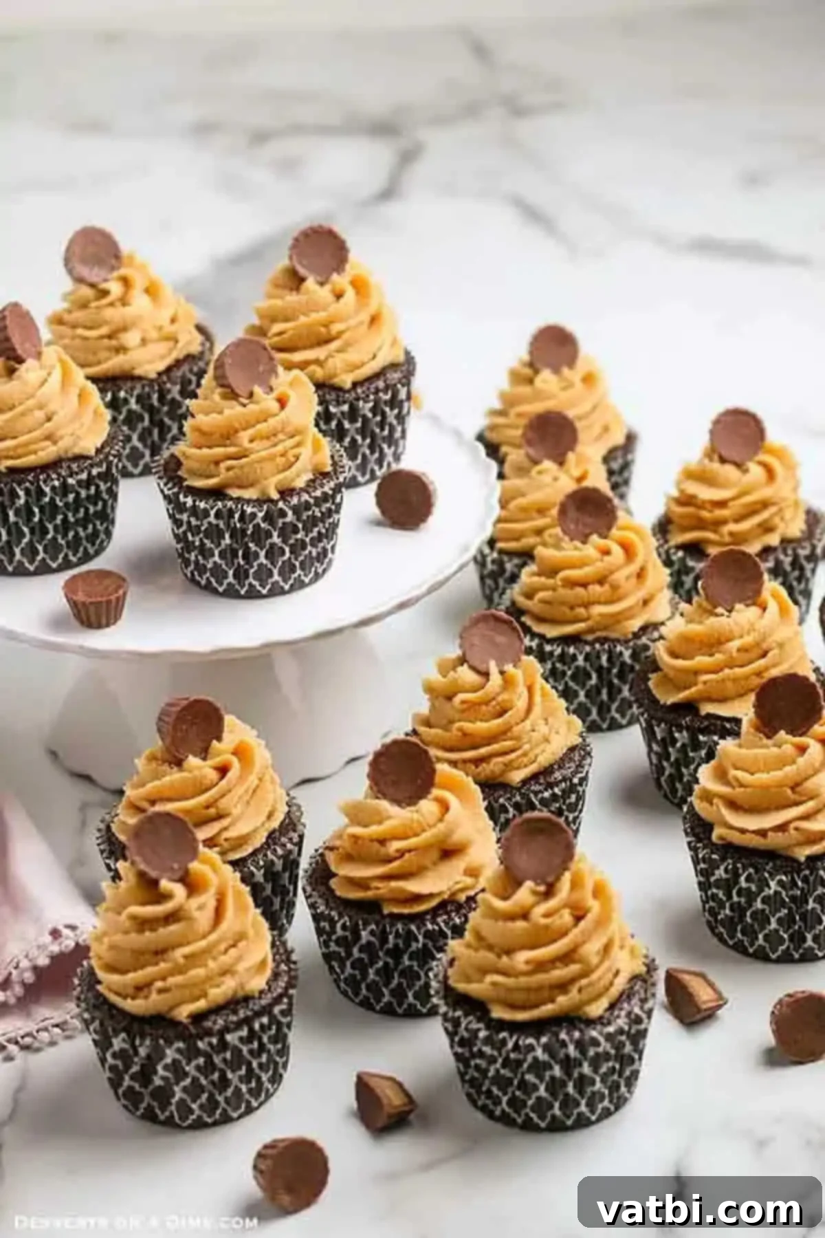 Chocolate and peanut butter fans will go crazy over Chocolate cupcakes with peanut butter frosting. Each bite is moist and delicious and so decadent. This recipe for homemade cupcakes makes baking from scratch easy. Try the best cupcakes with dark chocolate and peanut butter today. #dessertonadime #chocolatepeanutbuttercupcakes Chocolate and peanut butter cupcakes topped with Reese's Peanut Butter Cups