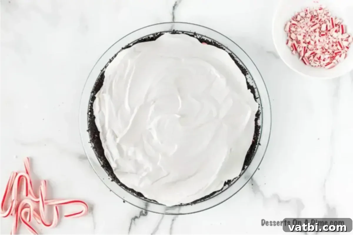 Simple Swirl Candy Cane Pie 4 Whipped cream being spread smoothly over the peppermint pie filling.