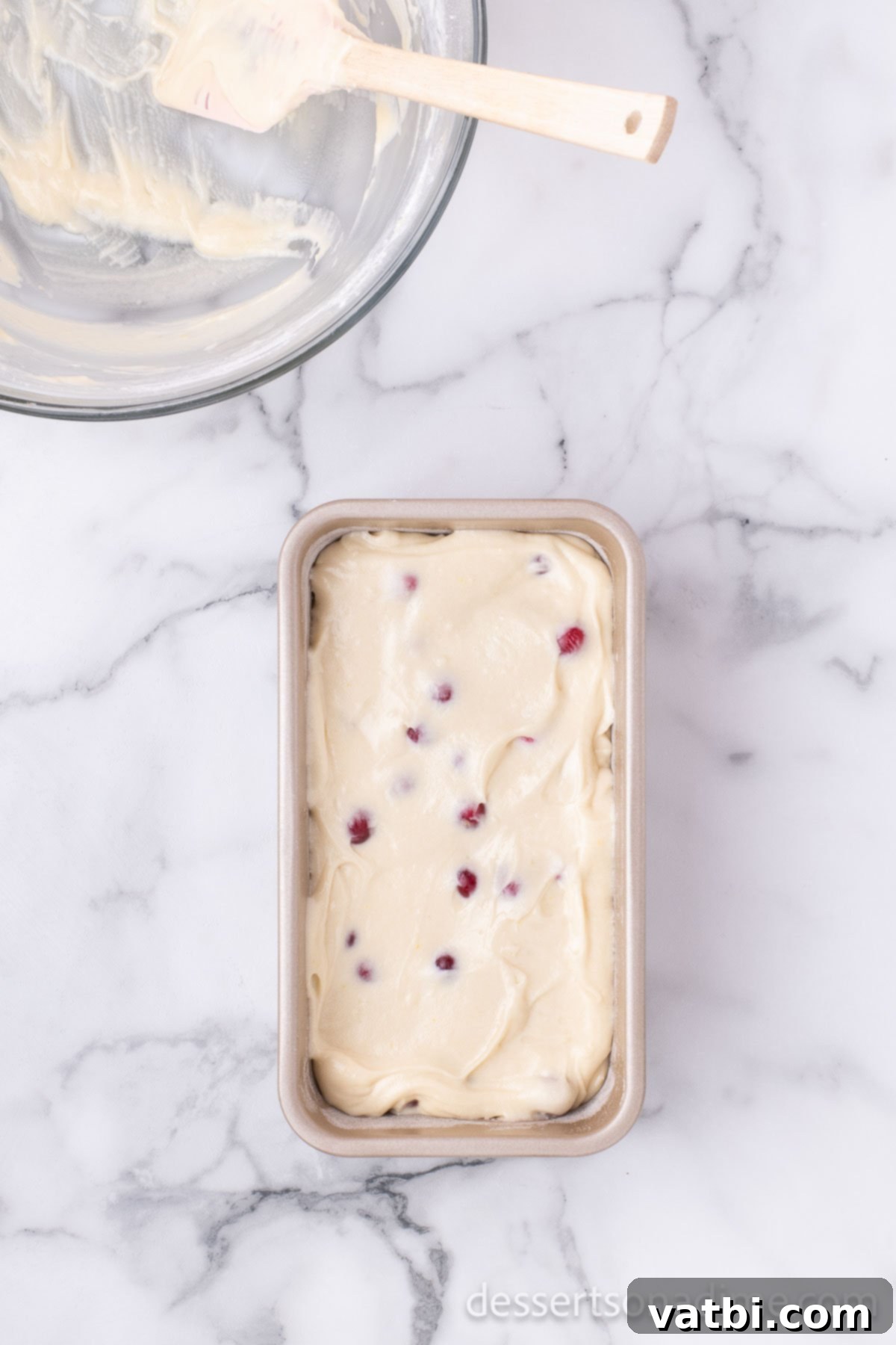 Loaf pan filled with cranberry bread batter, ready for baking.