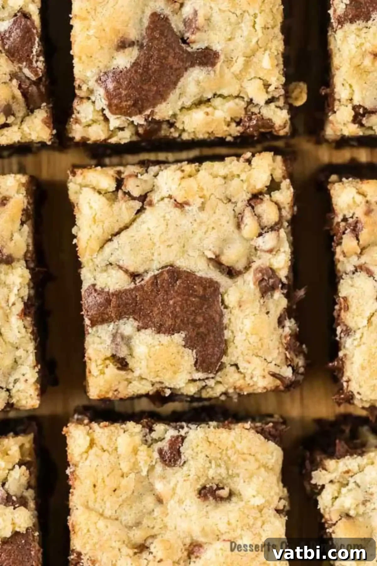 Delicious squares of homemade brookies on a rustic wooden cutting board, showcasing both brownie and chocolate chip cookie layers.