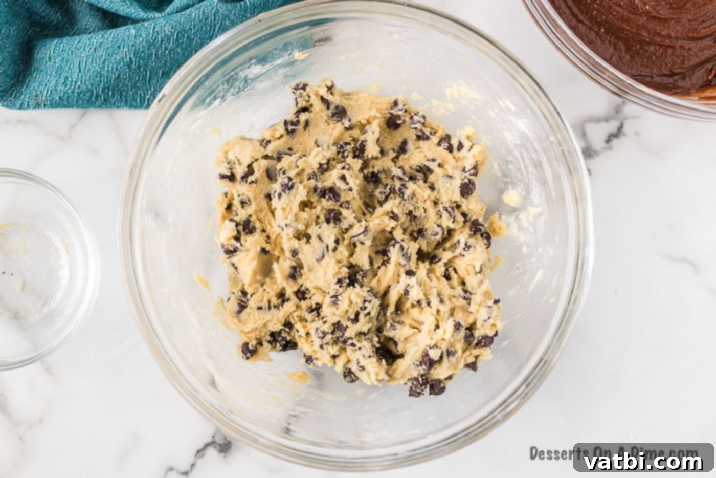 Close-up of chocolate chip cookie dough being mixed in a bowl.