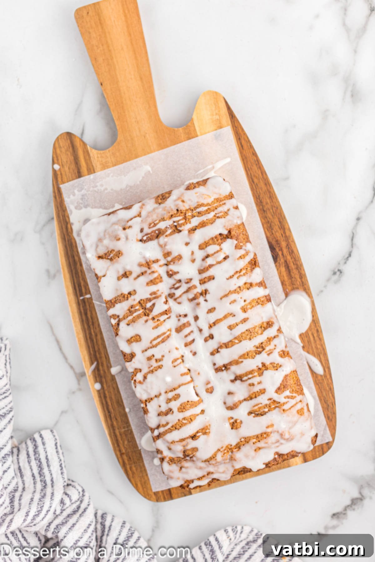 Cinnamon Swirl Bread 10 Bread on parchment paper with glaze drizzled on bread.