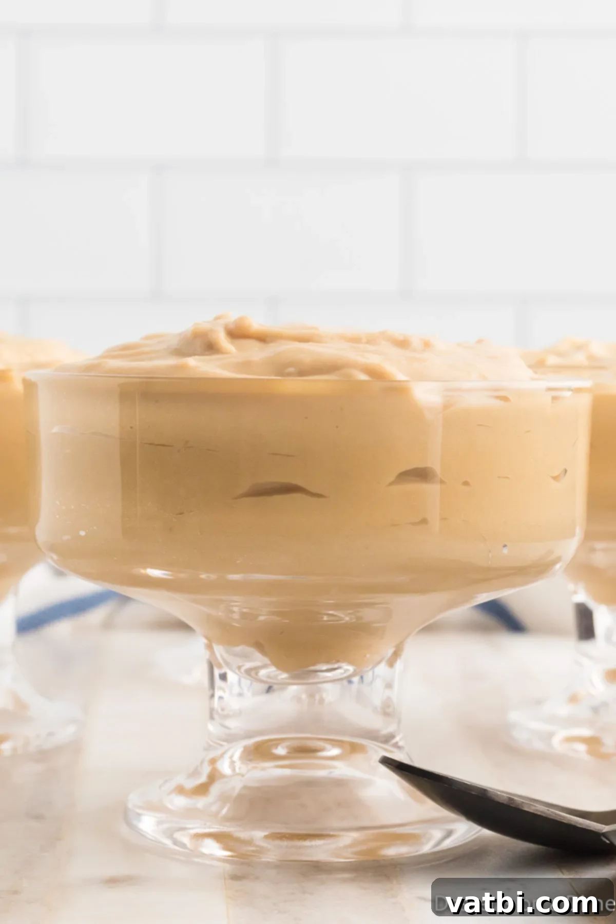 Creamy Butterscotch Bliss 11 Close-up of a serving of butterscotch pudding in a glass cup, showing its smooth texture.
