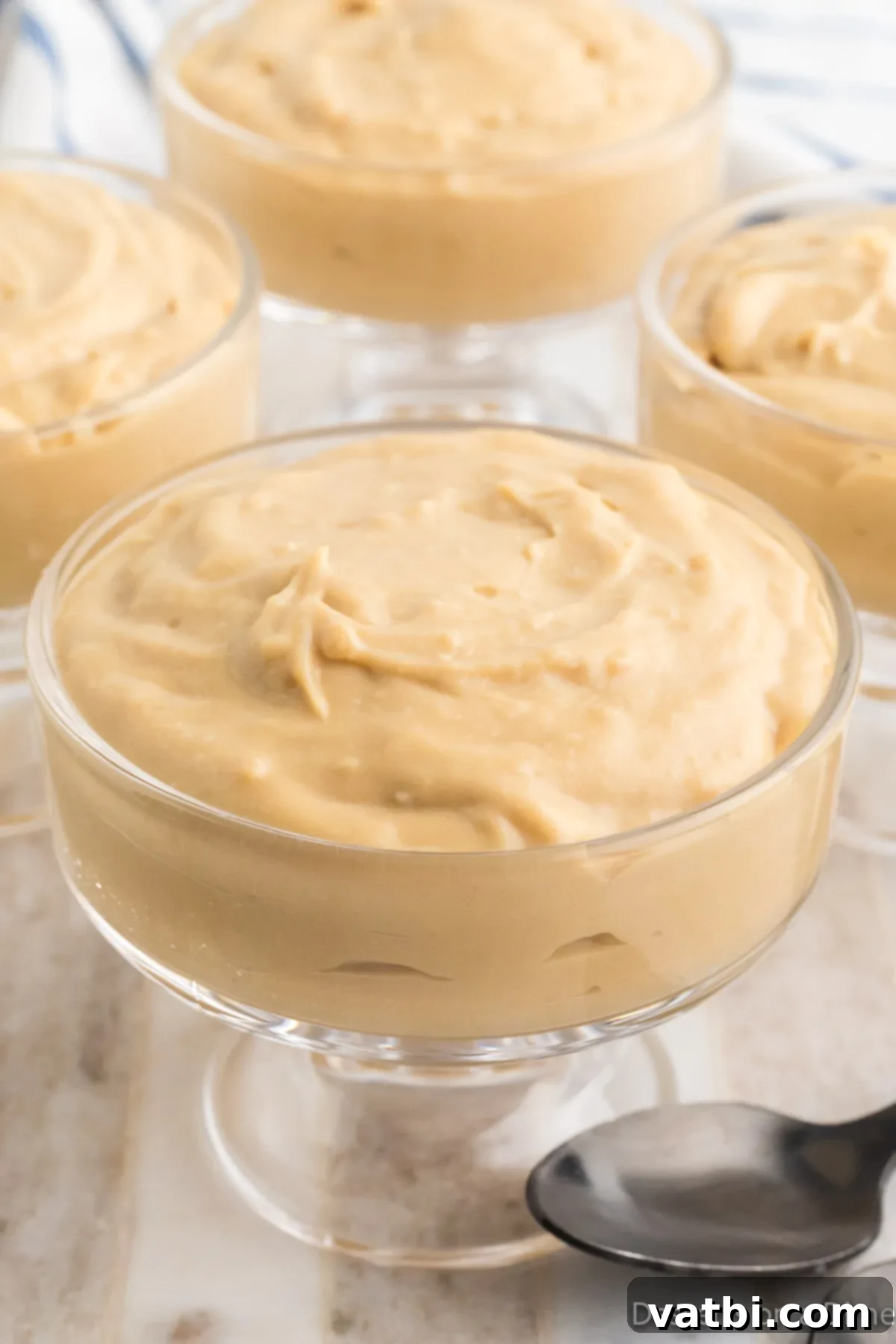 Creamy Butterscotch Bliss 10 Individual serving of butterscotch pudding in a cup with a spoon, highlighting its creamy texture.