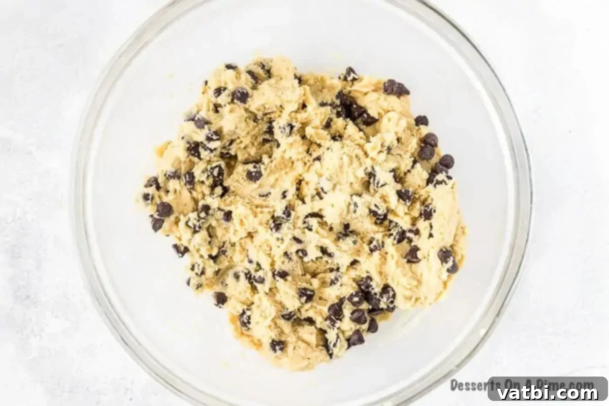 Close-up of golden cookie dough mixed together in a large bowl, showing its soft, uniform texture before chocolate chips are added.