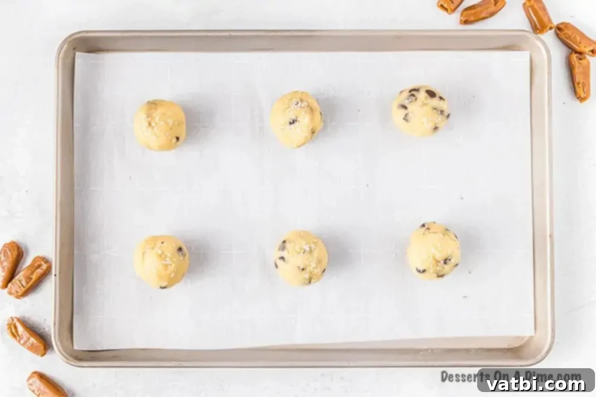 A cookie dough ball completely enclosing a soft caramel piece, perfectly formed and ready for baking, showcasing a smooth exterior.