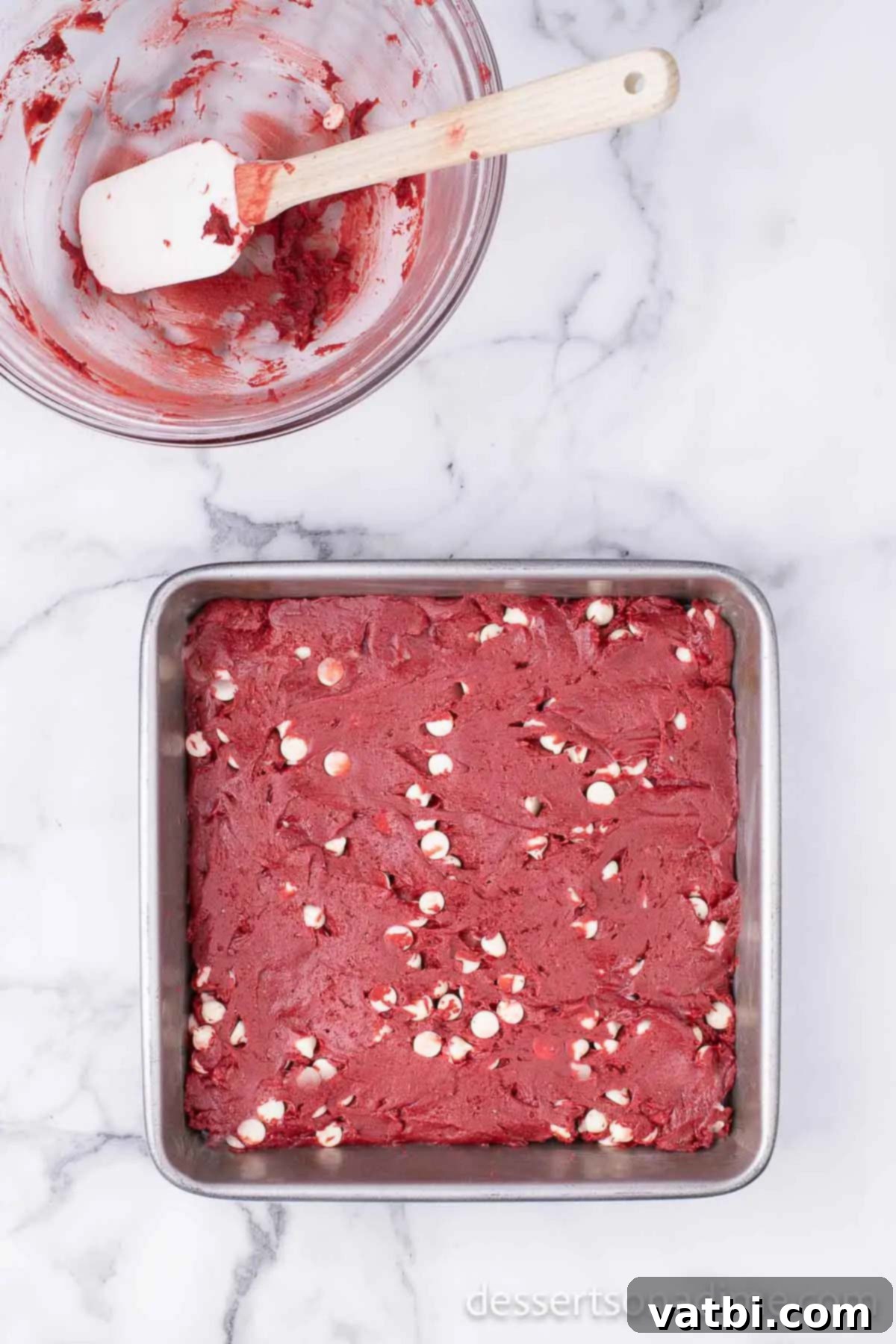 Velvet Red Brownie Bliss 4 Spreading vibrant red velvet brownie batter evenly into a prepared baking dish.