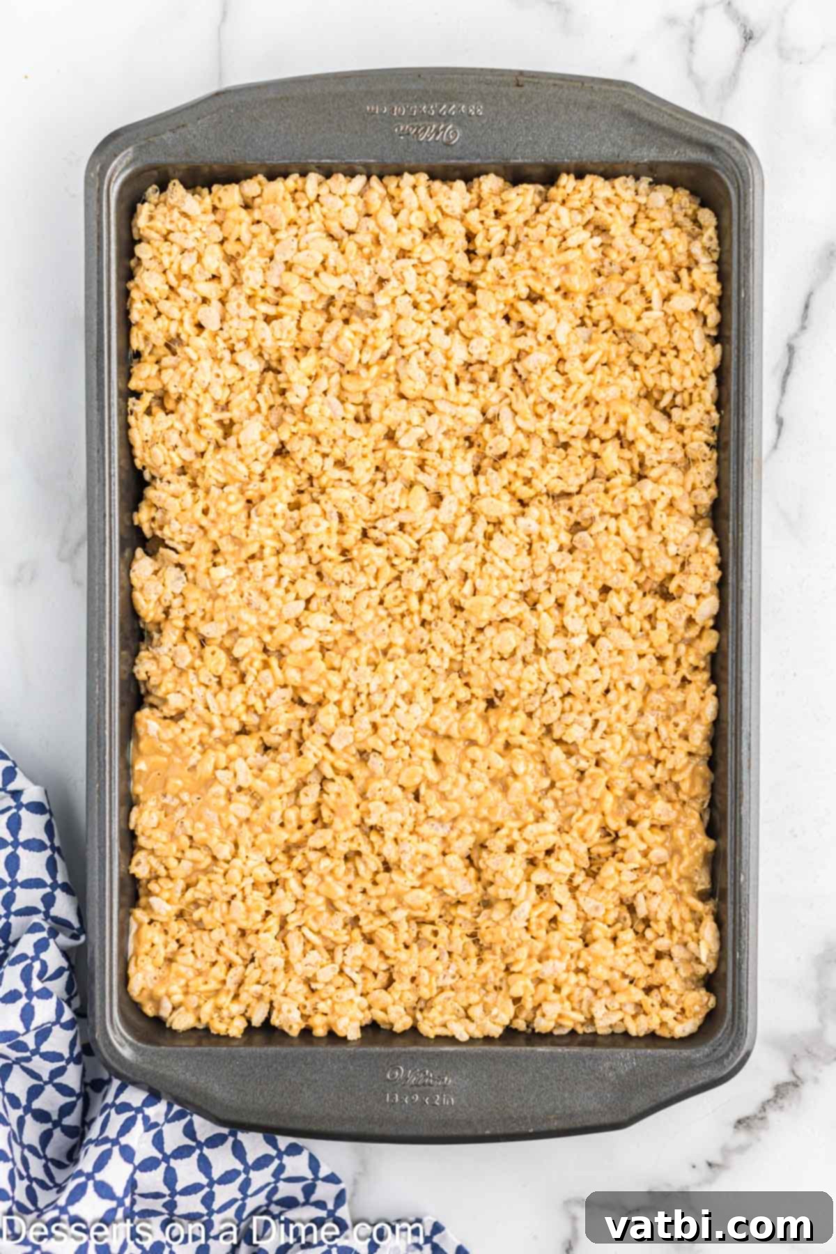 Chewy Peanut Butter Rice Krispie Treats 6 The peanut butter Rice Krispie mixture being pressed into a prepared baking pan.
