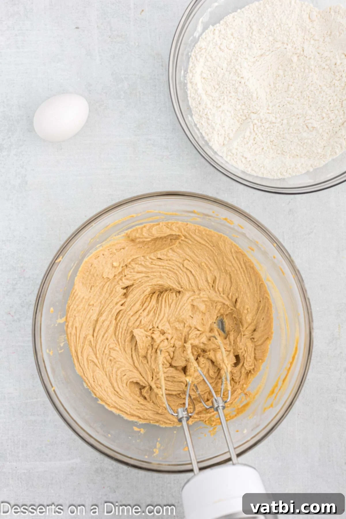 A stand mixer combining butter, brown sugar, peanut butter, milk, and vanilla extract in a large bowl.