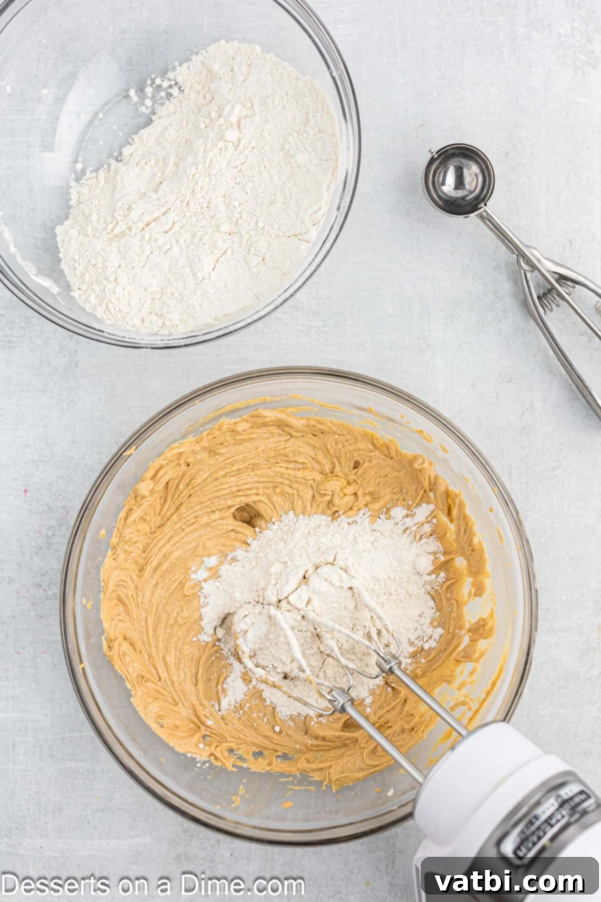 Dry ingredients, including flour, baking soda, and salt, being gradually added to the wet ingredients in a mixer.