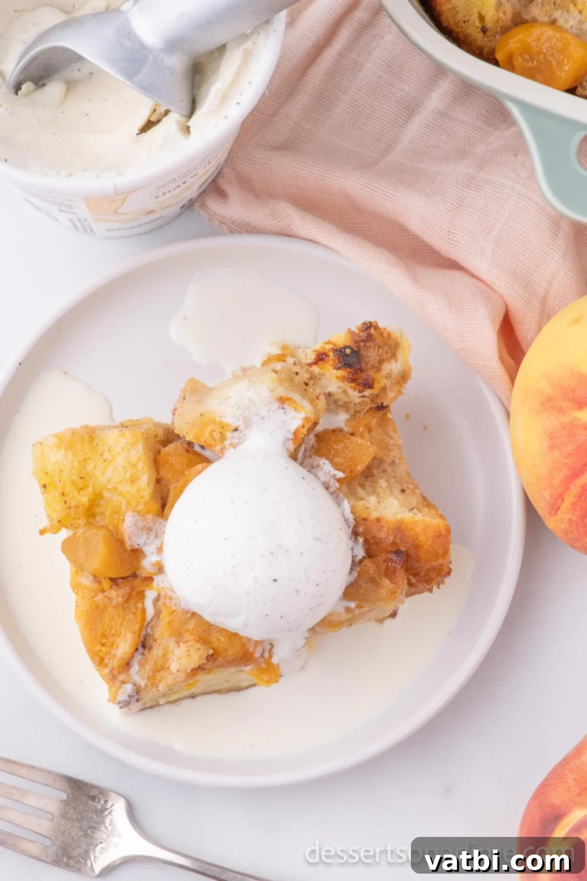 Golden Peach Bread Pudding 11 Close-up of peach bread pudding topped with ice cream, showcasing its golden crust and soft interior.