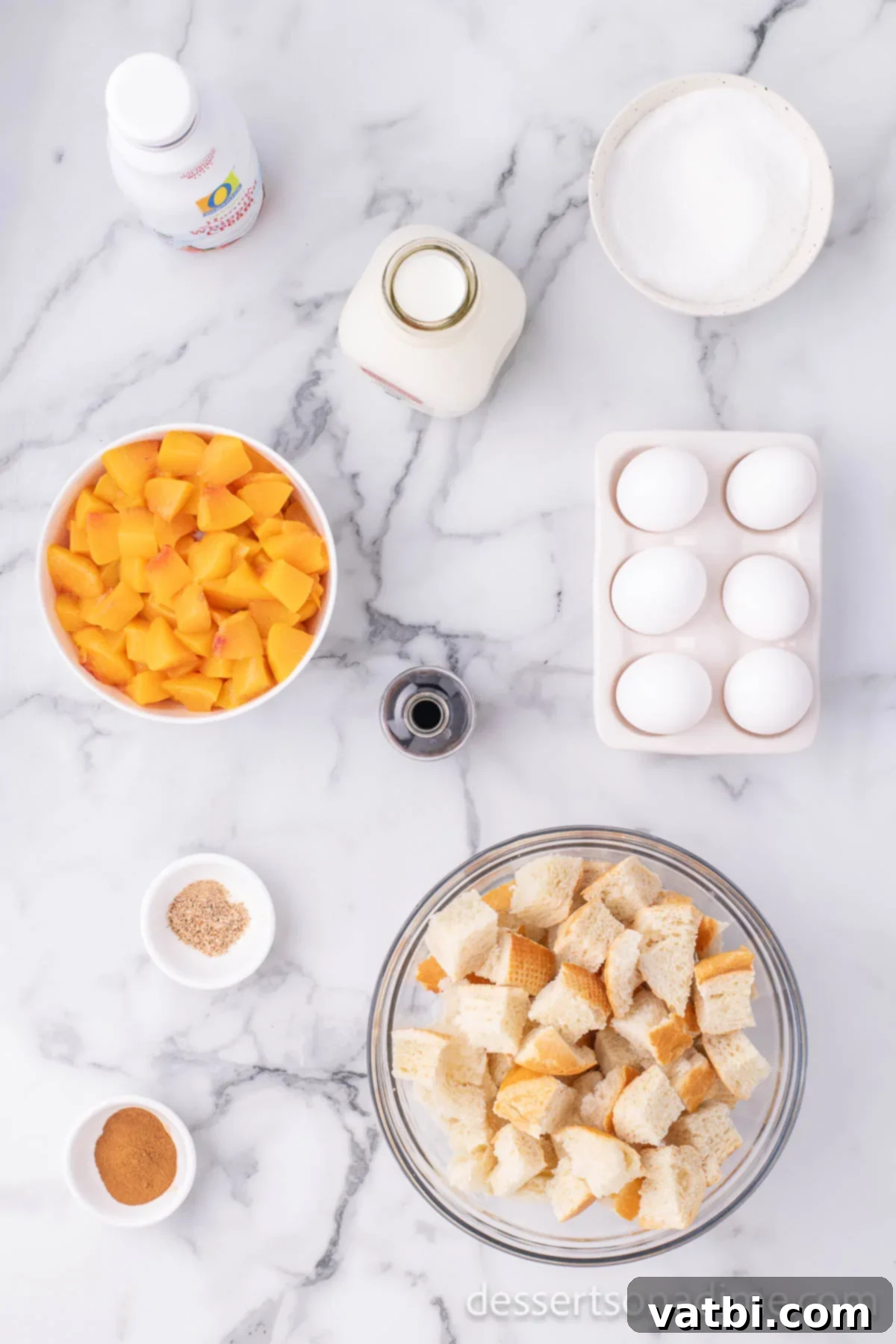 Golden Peach Bread Pudding 3 Arrangement of bread cubes, eggs, whole milk, heavy cream, sugar, vanilla extract, ground cinnamon, ground nutmeg, and fresh peaches on a white surface.
