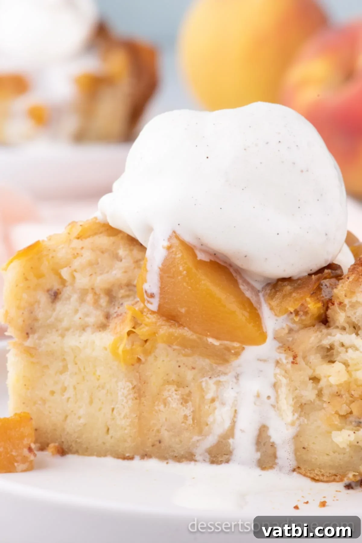 Golden Peach Bread Pudding 4 A slice of warm peach bread pudding served in a bowl, topped with a scoop of vanilla ice cream and drizzled with caramel sauce.