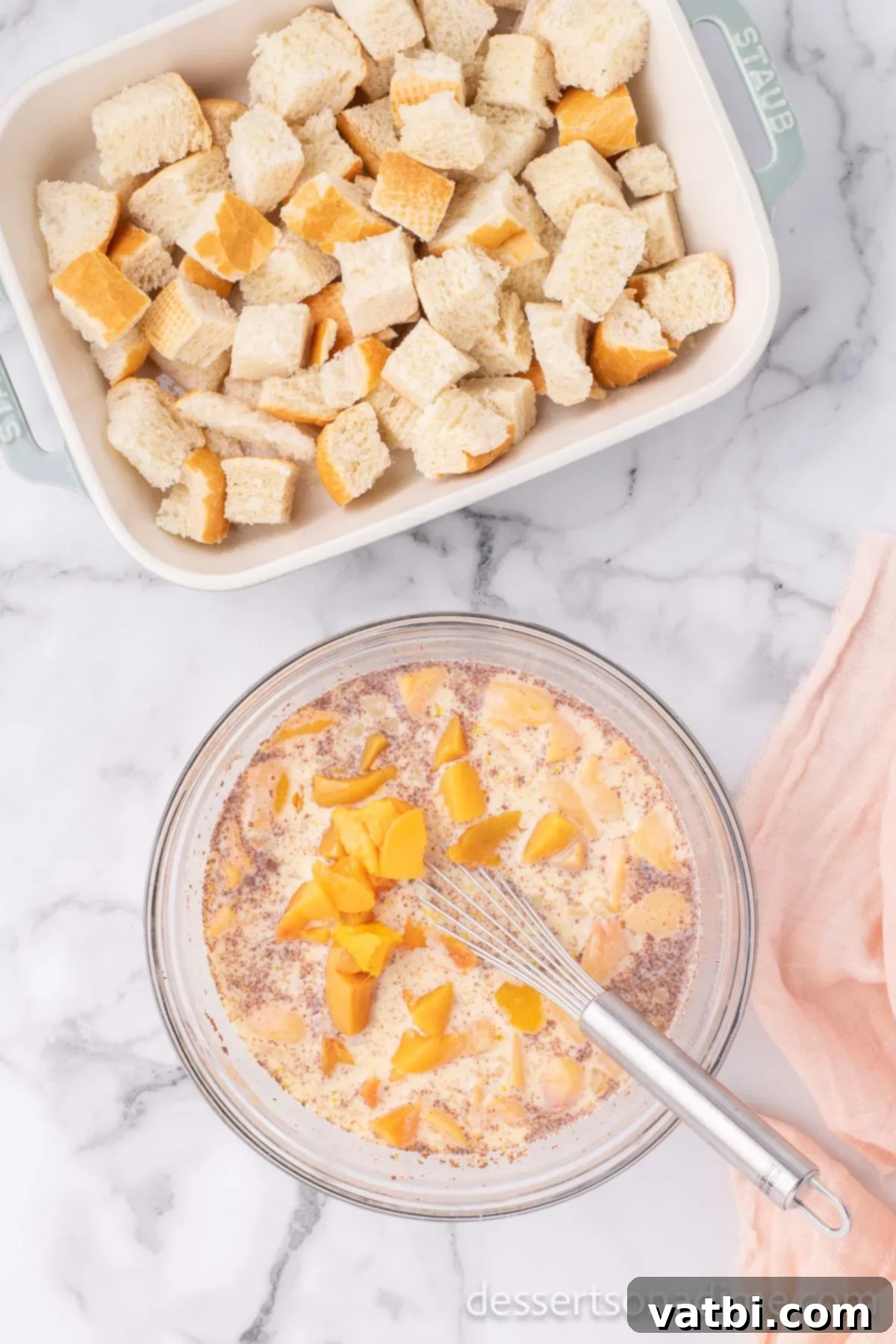 Golden Peach Bread Pudding 7 Diced fresh peaches being added to the custard mixture in a mixing bowl.
