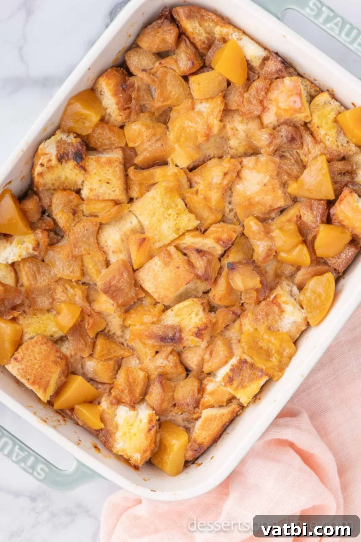 Golden Peach Bread Pudding 9 Baked peach bread pudding in a casserole dish, golden brown and set.