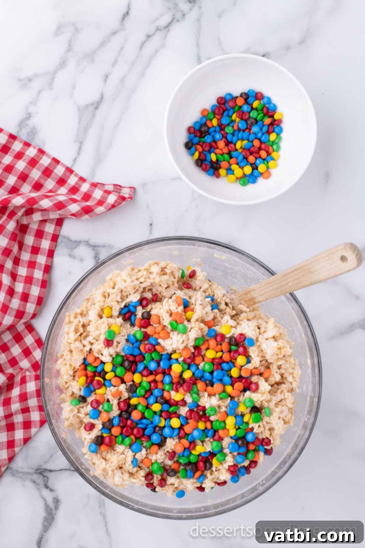 Rainbow Chocolate Krispie Squares 6 Mini M&M candies being gently folded into the cereal and marshmallow mixture.