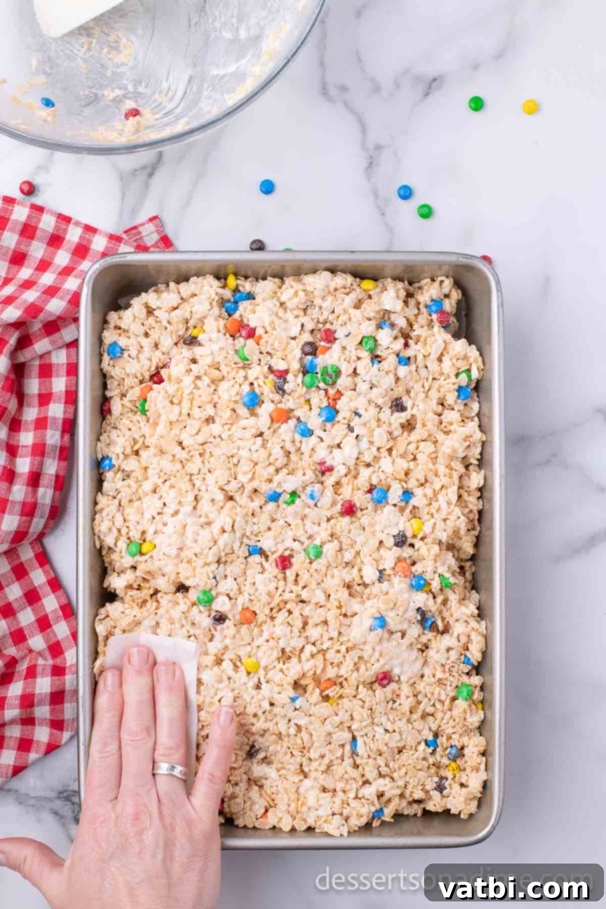 Rainbow Chocolate Krispie Squares 7 M&M Rice Krispie Treat mixture spread evenly into a baking dish, ready to set.