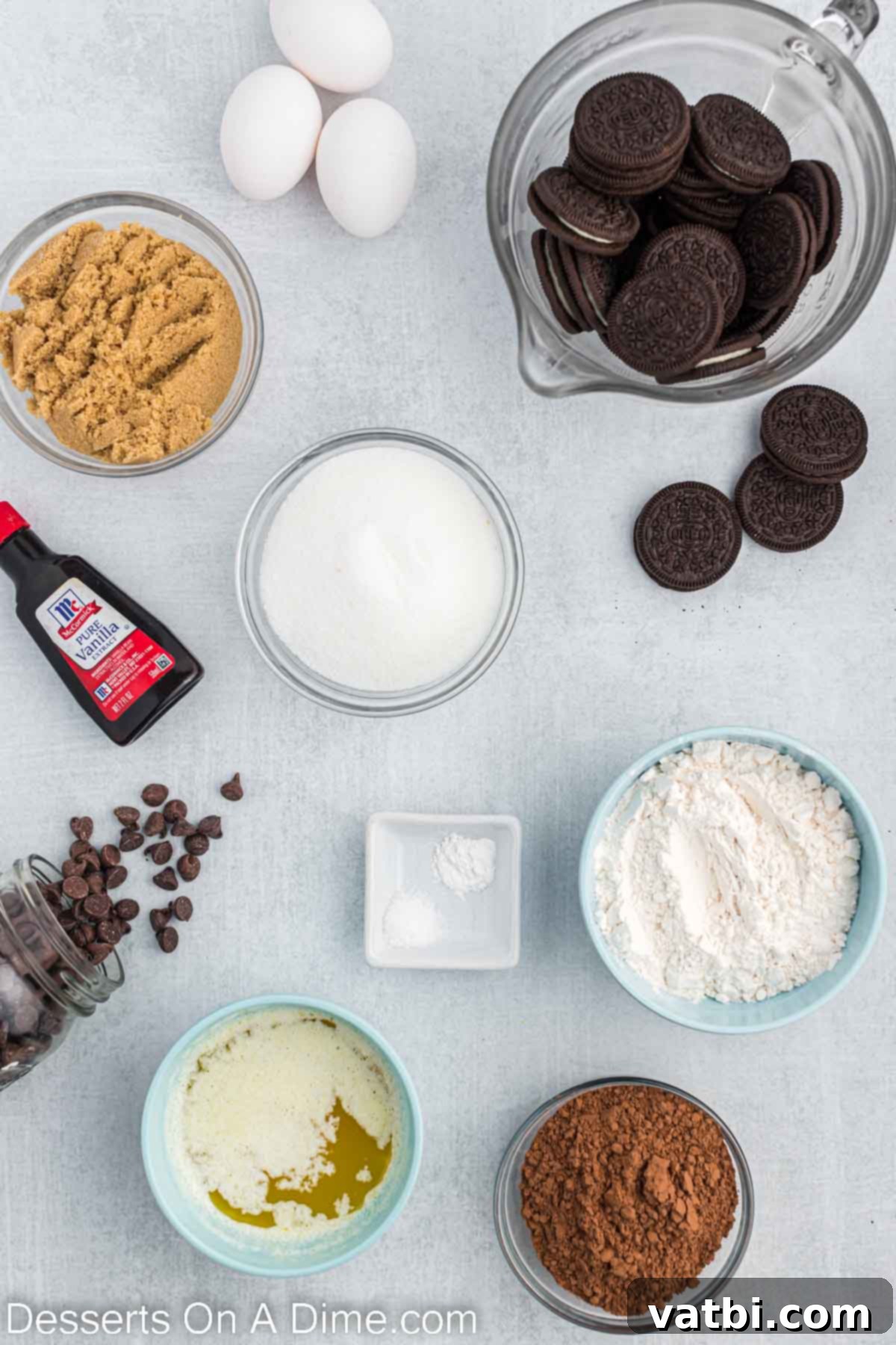 Jazz up plain brownies with Oreo cookies in this homemade Oreo brownies recipe. This delicious combination is a dream for Oreo fans and so simple. Oreo brownies recipe is one of the best oreo desserts. #dessertonadime #oreobrownies #fudge #dessertrecipes A flat lay photograph displaying all the ingredients needed to make Oreo brownies: granulated sugar, brown sugar, unsweetened cocoa powder, all-purpose flour, salt, baking powder, eggs, butter, vanilla extract, semi-sweet chocolate chips, and Oreo cookies.