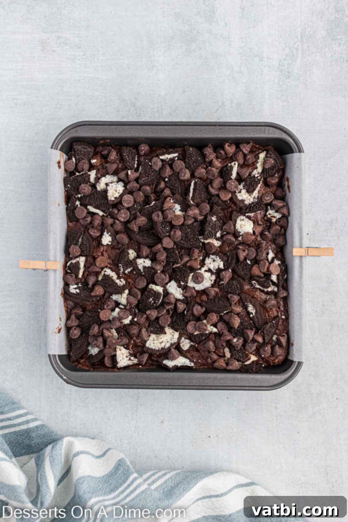 Decadent Oreo Brownies 7 The remaining brownie batter is poured over the Oreo cookie layer, completely covering them. Crushed Oreo pieces and extra chocolate chips are then sprinkled on top for a finishing touch.