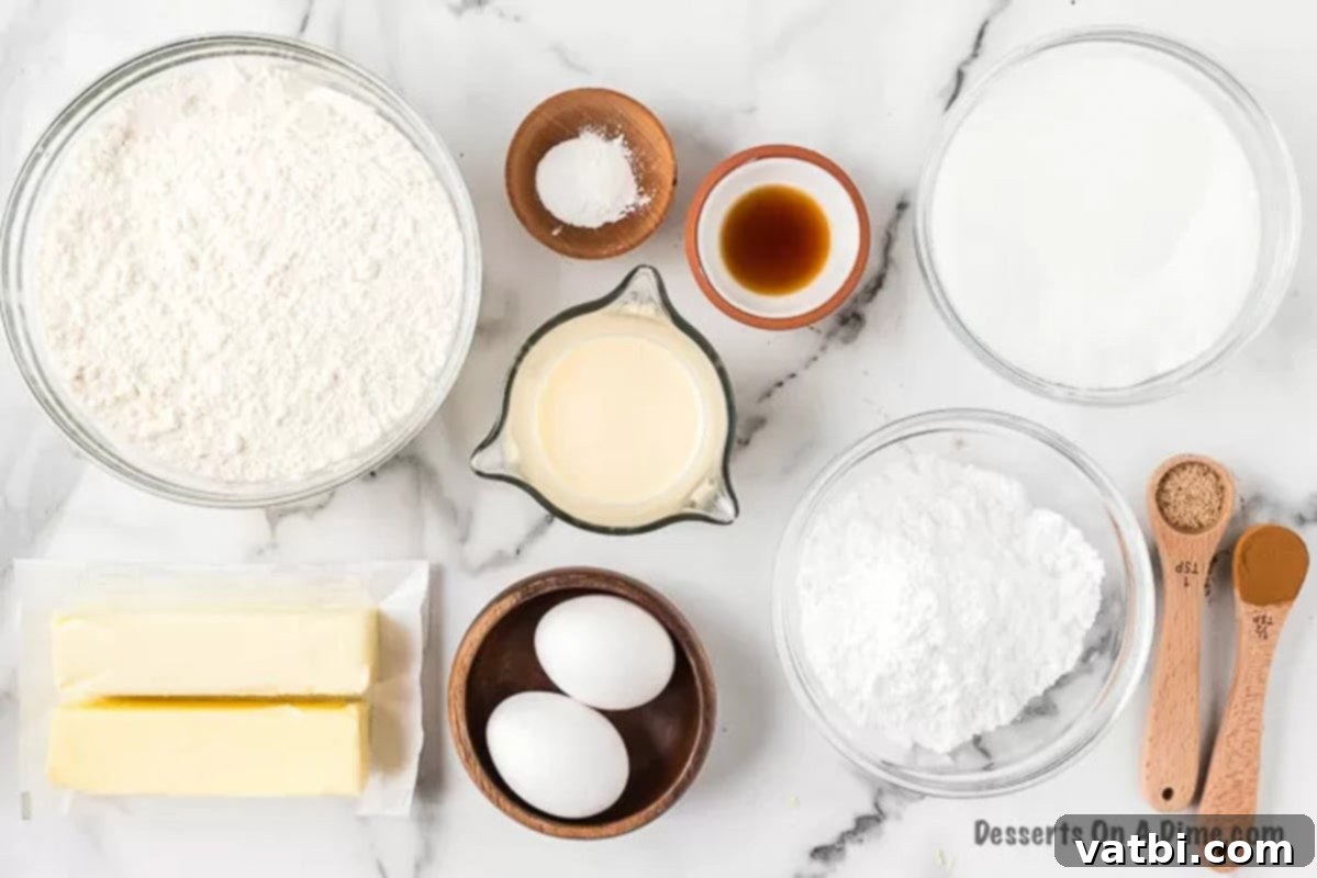 All the necessary ingredients to bake homemade eggnog sugar cookies and frosting. A selection of ingredients laid out, including butter, white sugar, eggs, flour, baking powder, nutmeg, cinnamon, eggnog, vanilla, and powdered sugar.