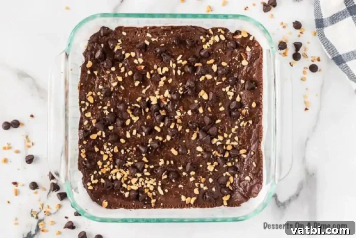 Fudge mixture spread into an 8x8 baking dish and topped with peanuts and chocolate chips.