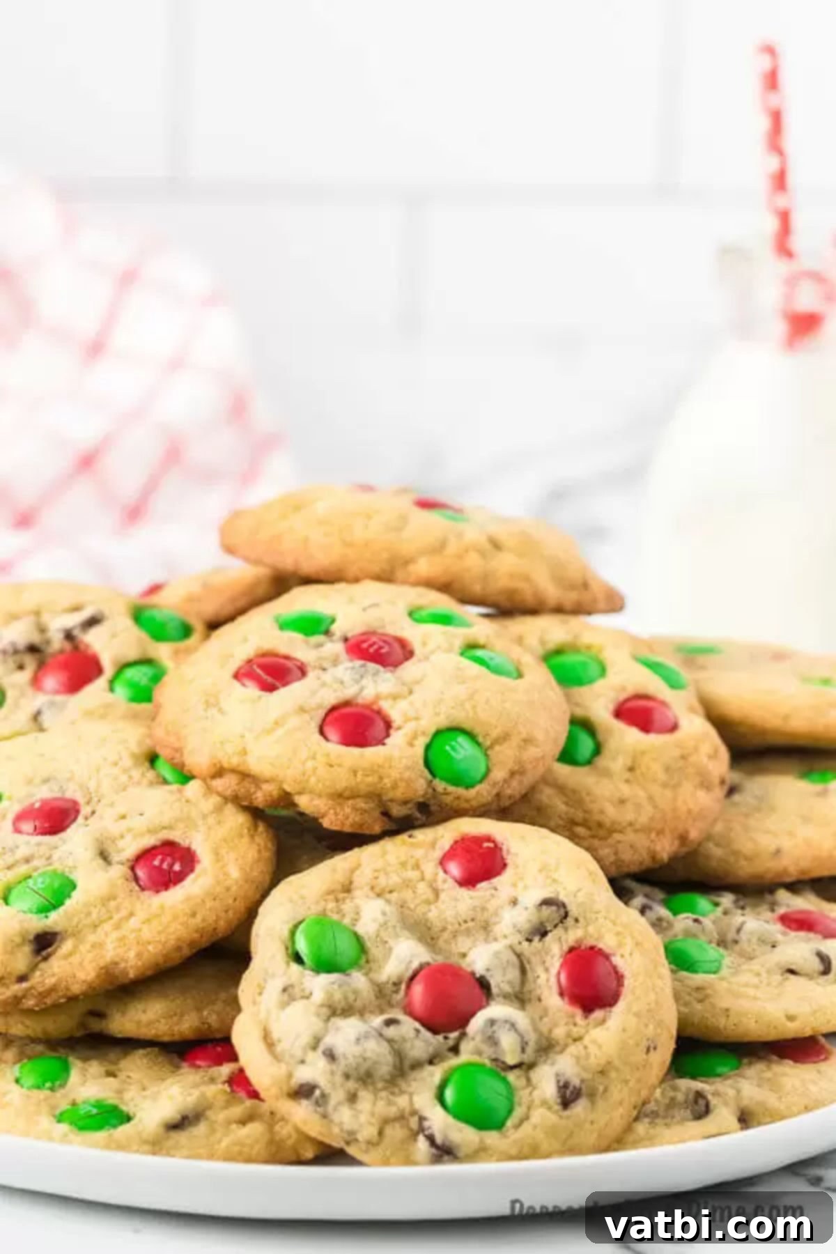 This easy Santa cookies recipe is sure to be a hit with lots of chocolate. These are the best cookies for Santa's plate and so simple. M&M Christmas Cookies are so easy to make for Christmas and combine chocolate chip and M&M candy. This is the perfect cookie for kids to put on Santa's platter. #dessertonadime #santacookiesrecipe #baking #kids Santa Cookies stacked on a plate