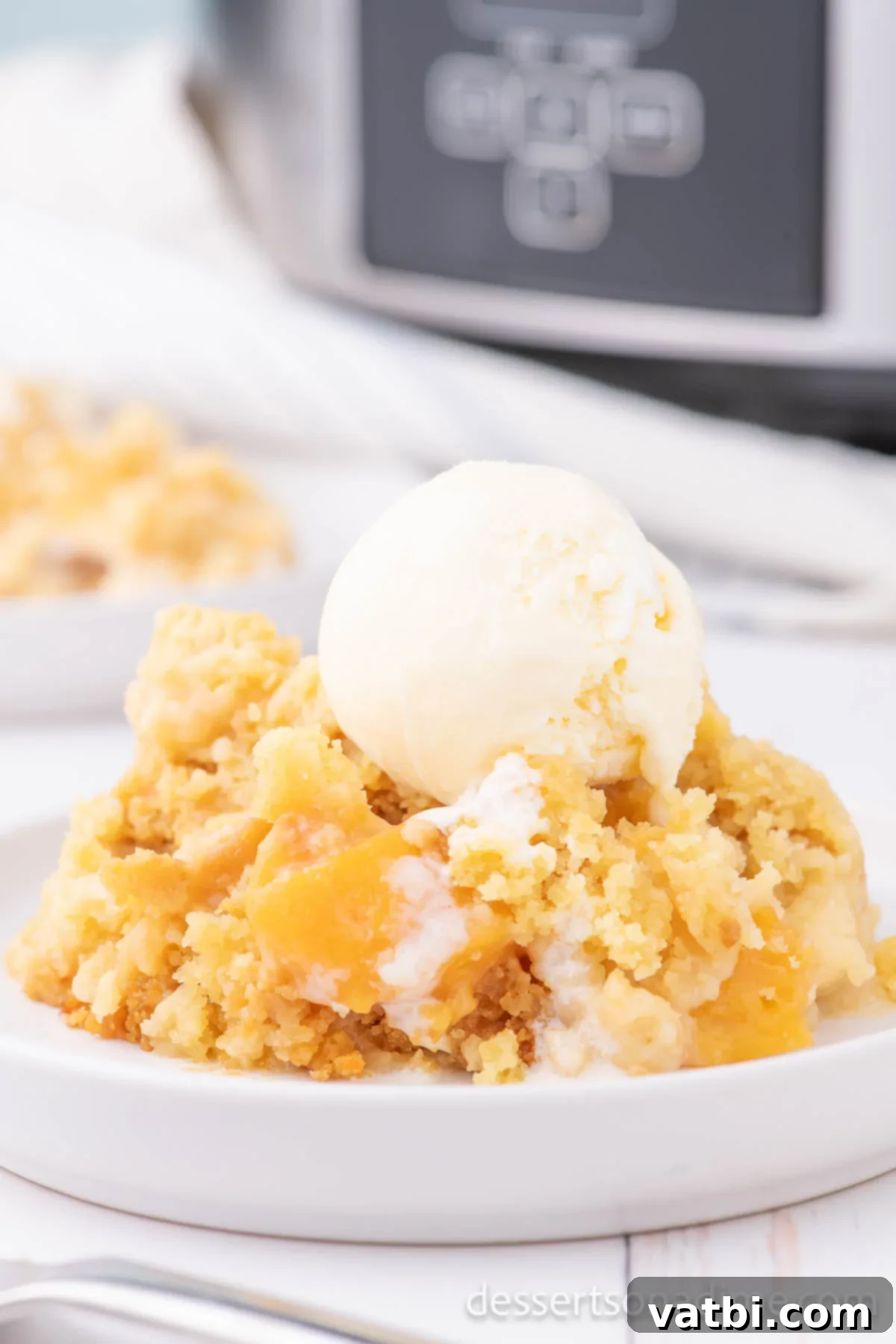 Effortless Slow Cooker Peach Delight 2 Bowl of Peach Dump Cake topped with ice cream.