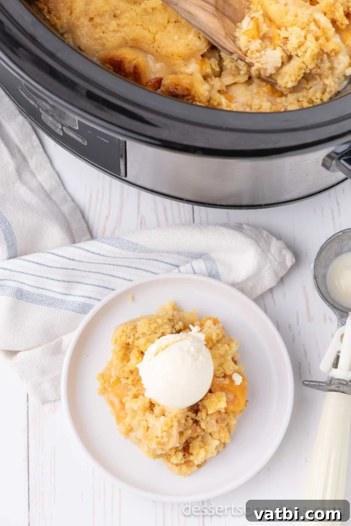 Effortless Slow Cooker Peach Delight 11 Peach Dump Cake topped with ice cream.