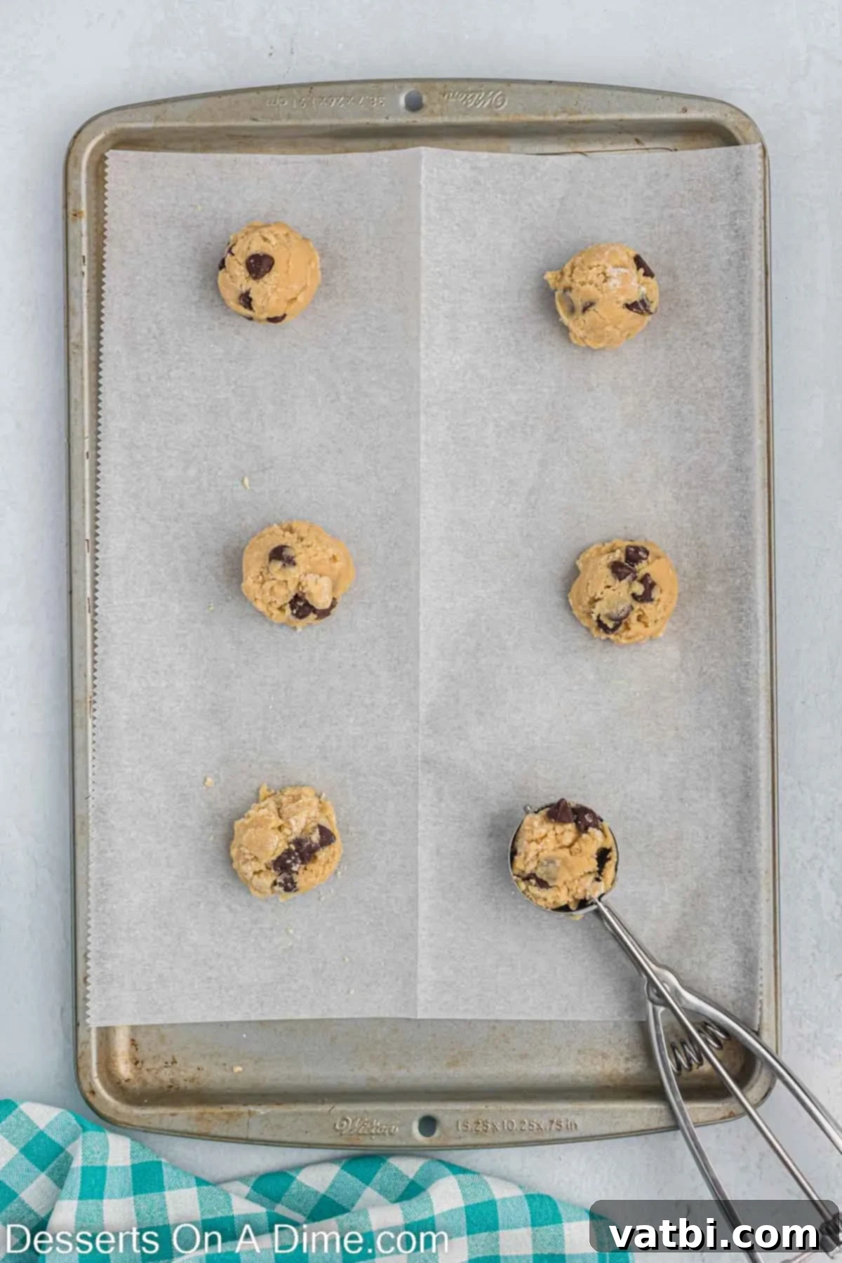 Effortless Chocolate Chip Perfection 4 Scoops of chocolate chip cookie dough balls neatly arranged on a baking sheet lined with parchment paper