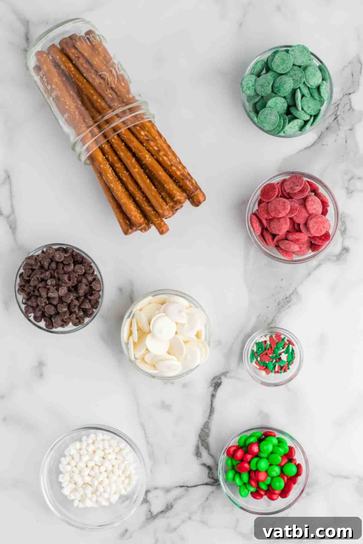 Homemade Christmas Chocolate Covered Pretzel Rods: An easy, tasty, and fun DIY holiday treat perfect for gifts or parties. Learn to make this festive chocolate-dipped pretzel recipe today! Ingredients for Christmas Chocolate Covered Pretzel Rods including pretzel rods, red, green, and white candy melts, chocolate chips, and various festive sprinkles and M&Ms