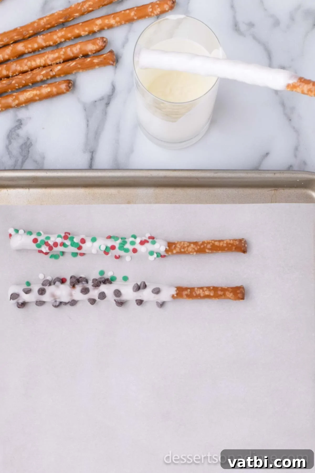 Sweet & Salty Holiday Pretzel Treats 2 Half-dipped pretzel rods laid out on a baking sheet lined with parchment paper
