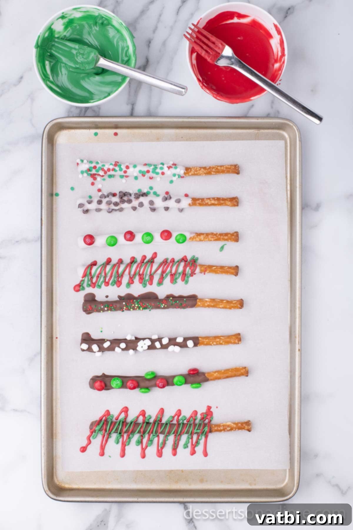 Sweet & Salty Holiday Pretzel Treats 5 Finished Christmas Chocolate Covered Pretzel Rods with various toppings and drizzles, cooling on a baking sheet