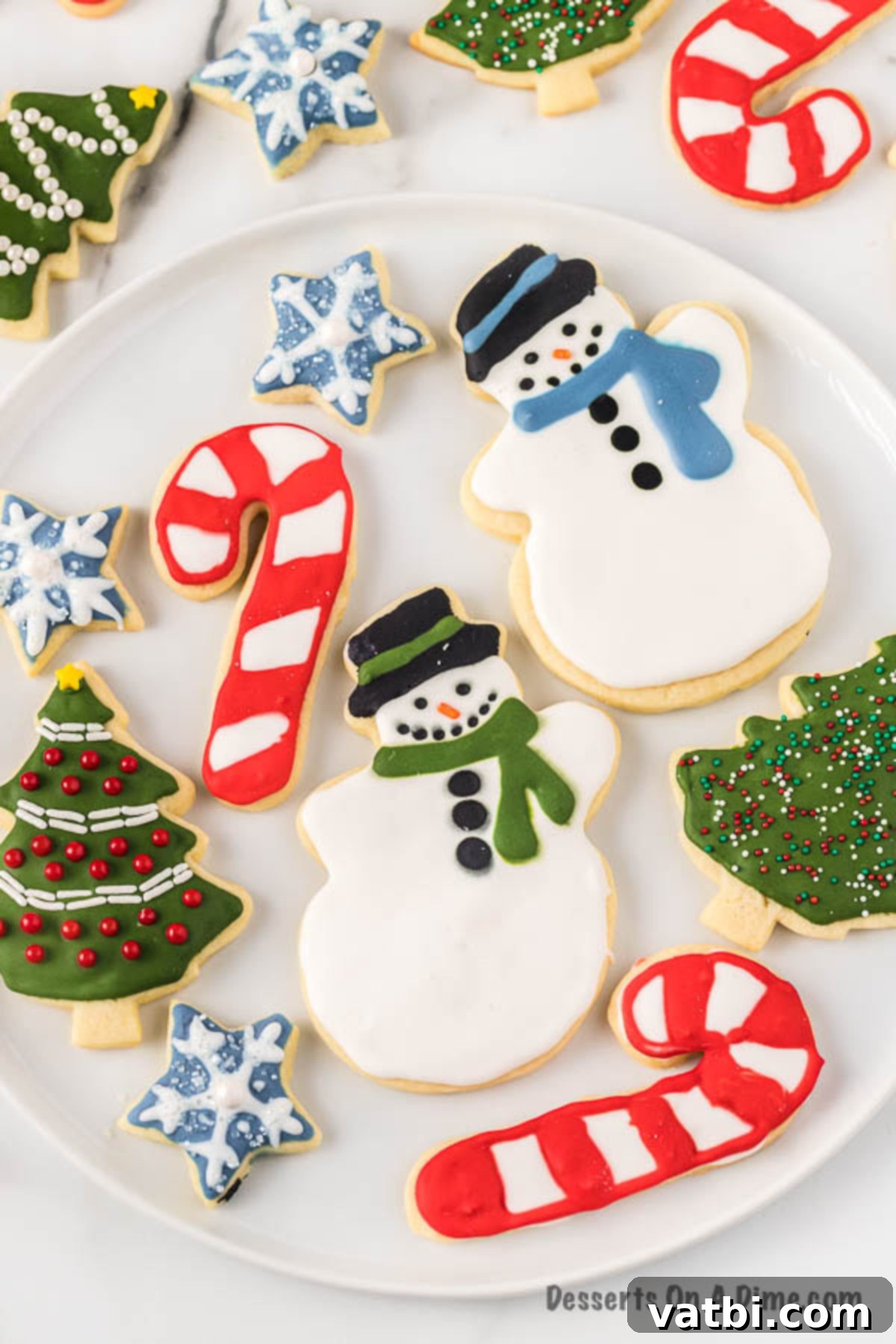 We have a recipe for the best cut out sugar cookies. Learn how to make perfect iced Christmas cut out sugar cookies in just a few easy steps. This cut out sugar cookies recipe is the best soft and chewy Christmas sugar cookies with royal icing. Once you learn how to make the best ever decorated moist and simple cut outs, you will make this a family tradition. #dessertonadime #bestcutoutsugarcookies #DecoratedforKids #decoratedeasy #cutouts #easysoft #good #softest Christmas Sugar Cookies decorated on a plate, showcasing festive designs.