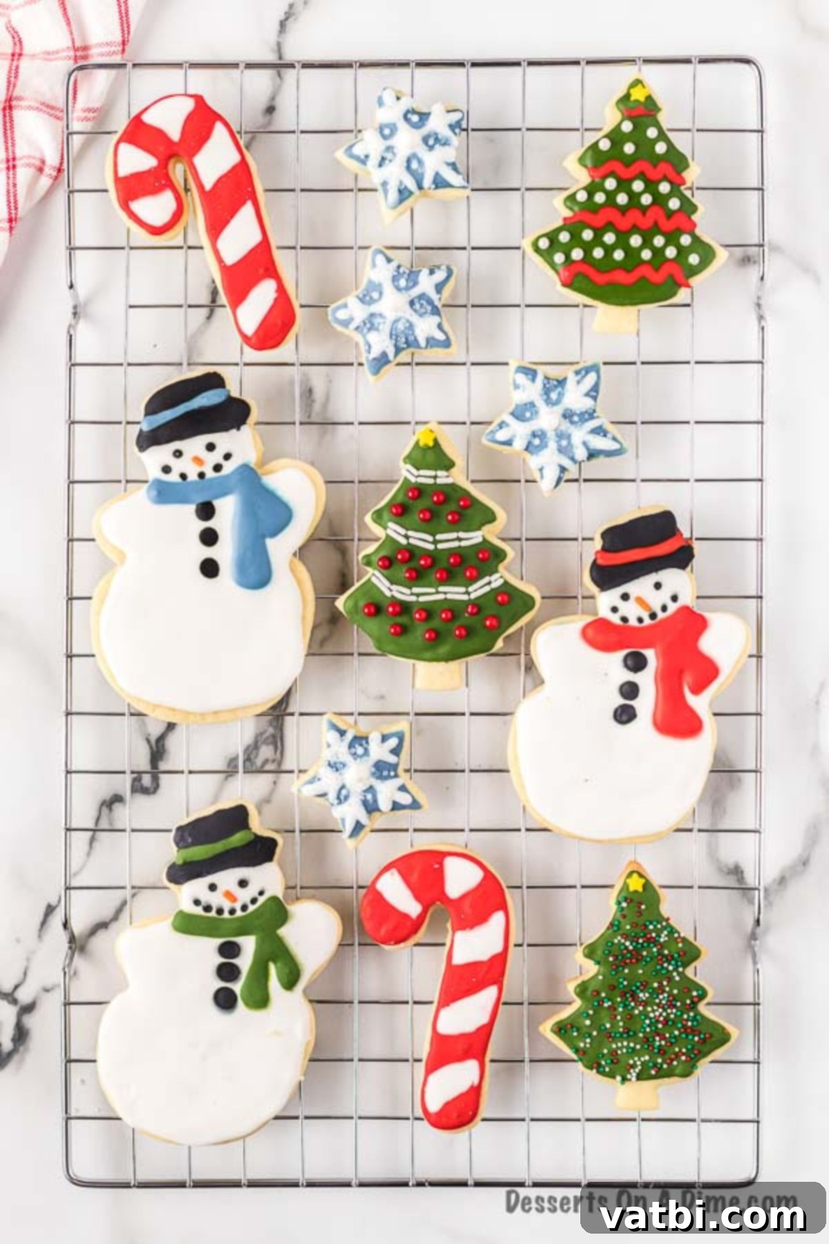 We have a recipe for the best cut out sugar cookies. Learn how to make perfect iced Christmas cut out sugar cookies in just a few easy steps. This cut out sugar cookies recipe is the best soft and chewy Christmas sugar cookies with royal icing. Once you learn how to make the best ever decorated moist and simple cut outs, you will make this a family tradition. #dessertonadime #bestcutoutsugarcookies #DecoratedforKids #decoratedeasy #cutouts #easysoft #good #softest Decorated sugar cookies drying on a cooling rack.