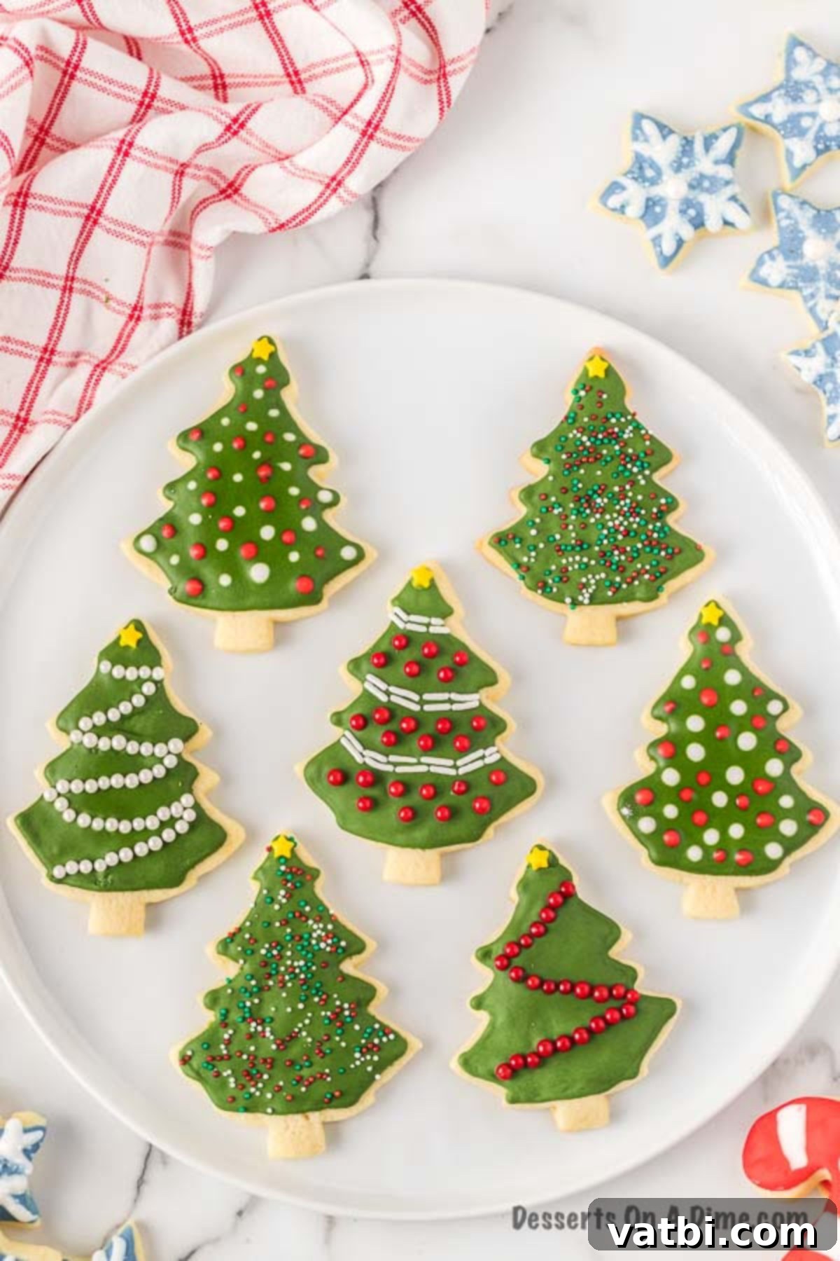 We have a recipe for the best cut out sugar cookies. Learn how to make perfect iced Christmas cut out sugar cookies in just a few easy steps. This cut out sugar cookies recipe is the best soft and chewy Christmas sugar cookies with royal icing. Once you learn how to make the best ever decorated moist and simple cut outs, you will make this a family tradition. #dessertonadime #bestcutoutsugarcookies #DecoratedforKids #decoratedeasy #cutouts #easysoft #good #softest Christmas Sugar Cookies decorated on a festive plate, ready for serving.