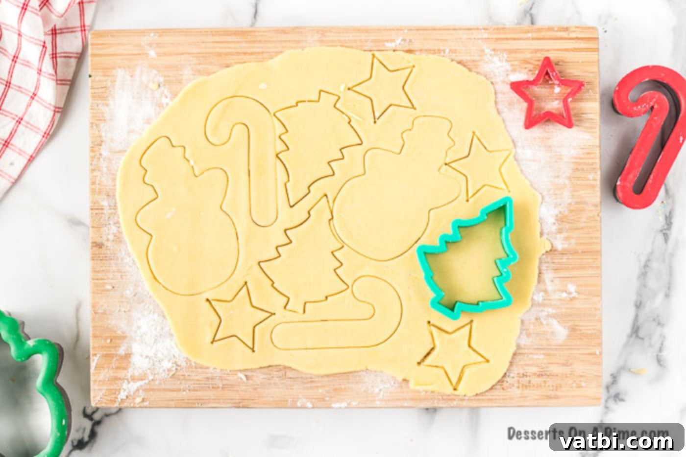 Festive Christmas Cut-Out Sugar Cookies 5 Rolled cookie dough with various Christmas cookie cutters.