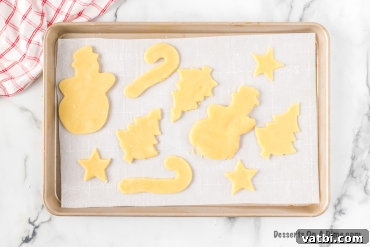 Festive Christmas Cut-Out Sugar Cookies 6 Unbaked cookies neatly arranged on a baking sheet.
