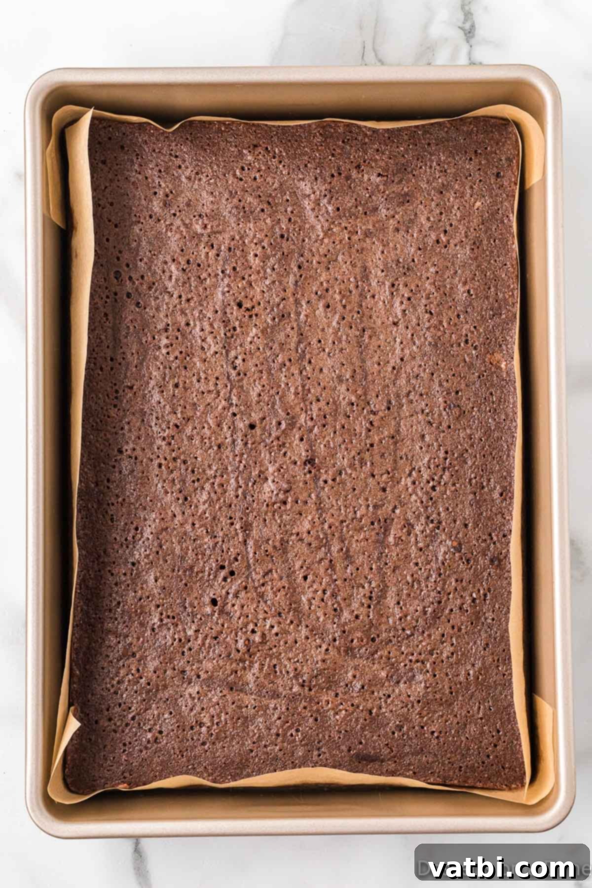 Sweetheart Brownie Delights 7 A batch of freshly baked brownies, golden brown and slightly cracked on top, cooling in the parchment-lined baking pan.