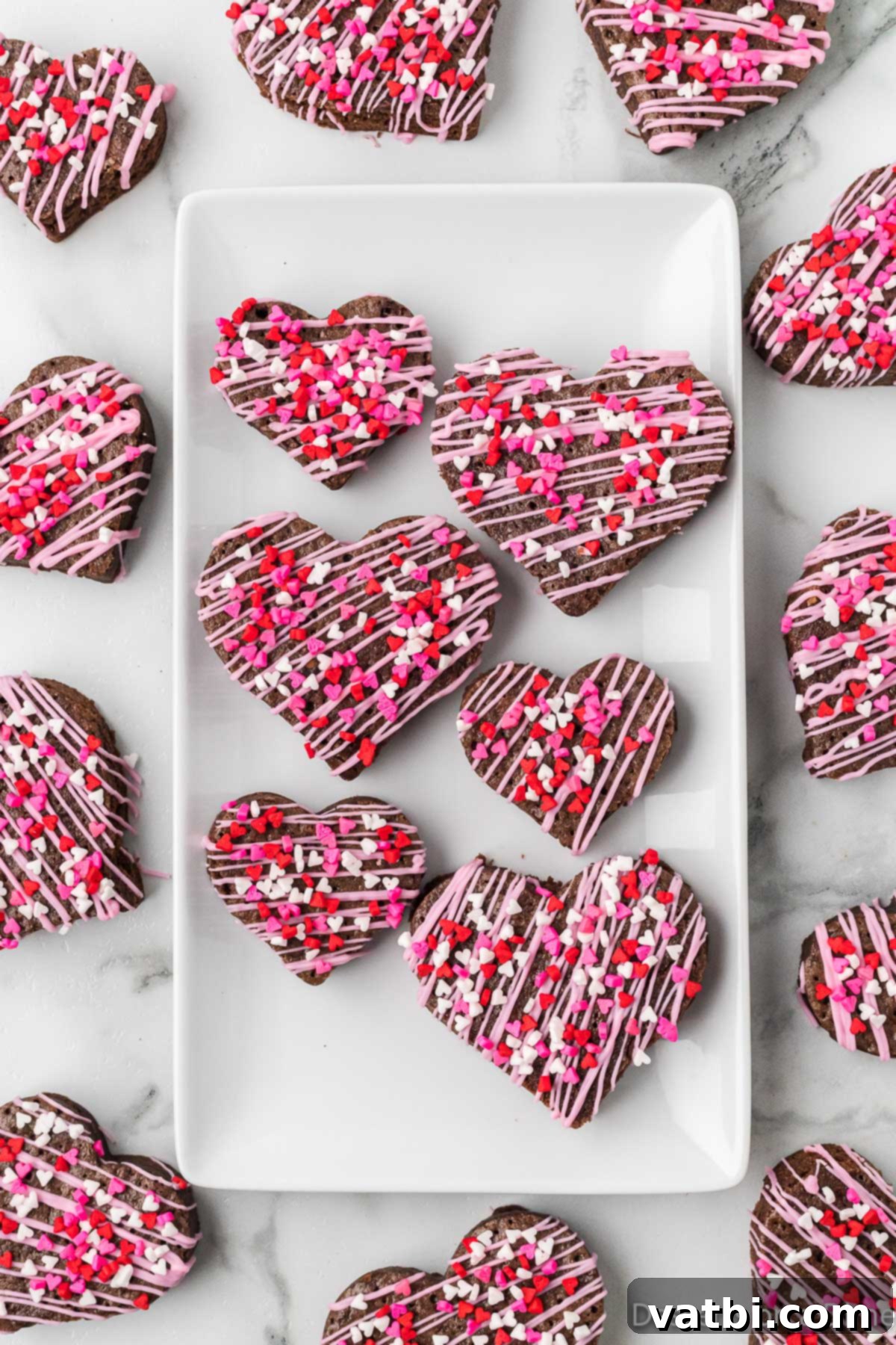 Sweetheart Brownie Delights 10 A charming platter of various heart-shaped brownies, some drizzled with pink candy melts and sprinkled with hearts, creating a delightful Valentine's Day display.