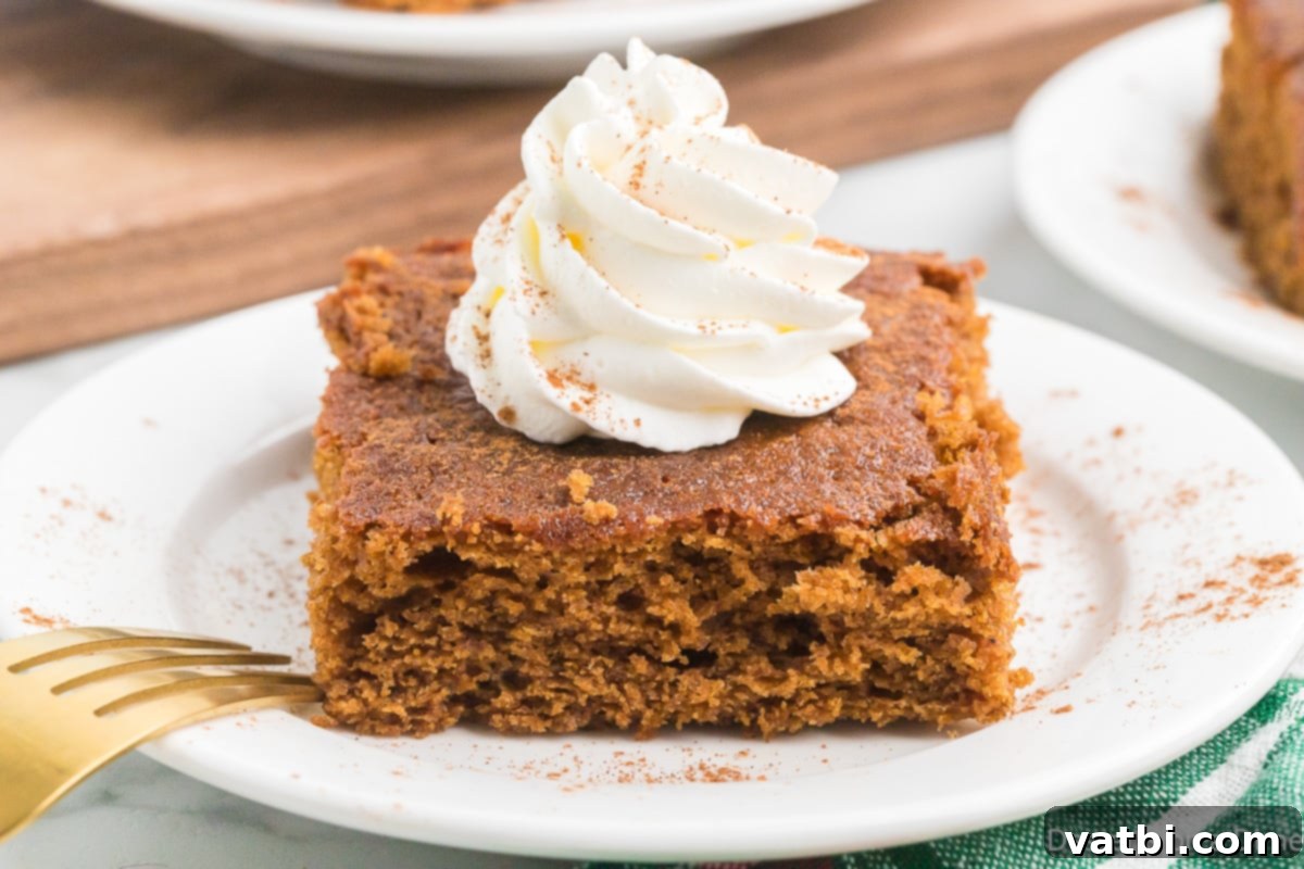 Moist Gingerbread Cake with Whipped Cream Slice of gingerbread cake on a plate topped with whipped cream, ready for a festive holiday treat