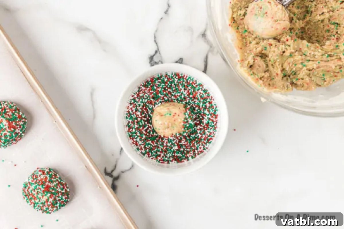 Festive Cake Mix Cookie Delights 3 Dough balls being rolled in sprinkles.