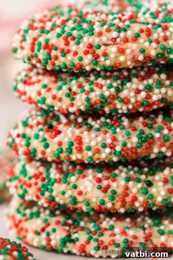 Christmas cake mix cookies make an easy and festive treat with only 4 ingredients. They are so light and fluffy for the perfect dessert. Learn how to make cake mix cookies with sprinkles. This is the best treat. #dessertonadime #ChristmasCakeMixCookies #Recipeseasy4ingredients #xmas #christmascakemixcookieseasy #recipes Christmas Cake Mix Cookies stacked with a bite taken out, showing the soft interior.