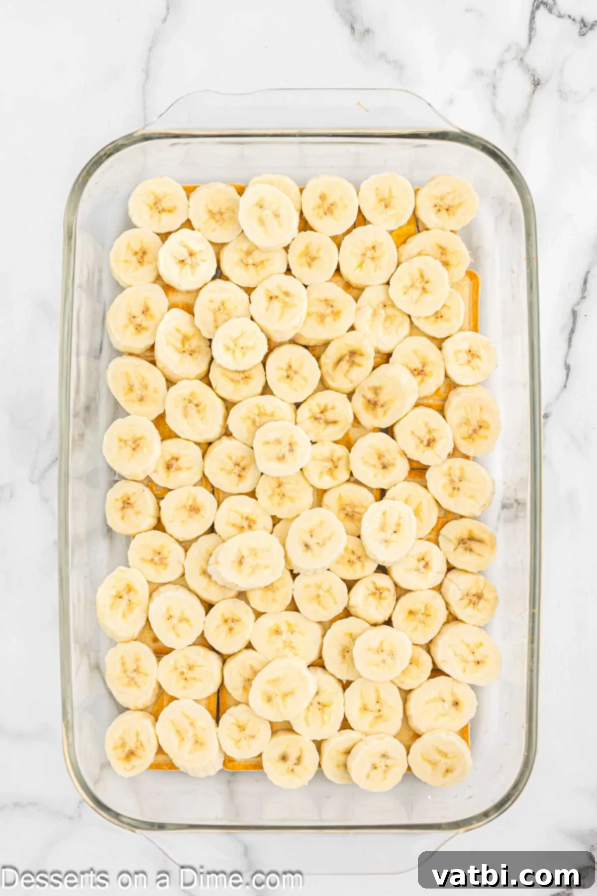 Slices of fresh banana layered neatly on top of the cookies in the baking pan.