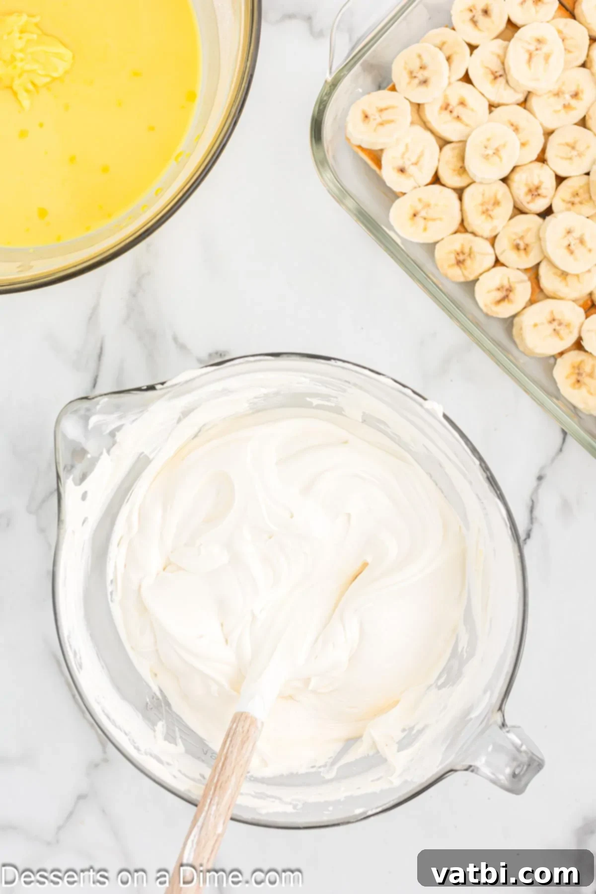 Whipped topping being gently folded into the cream cheese and condensed milk mixture.