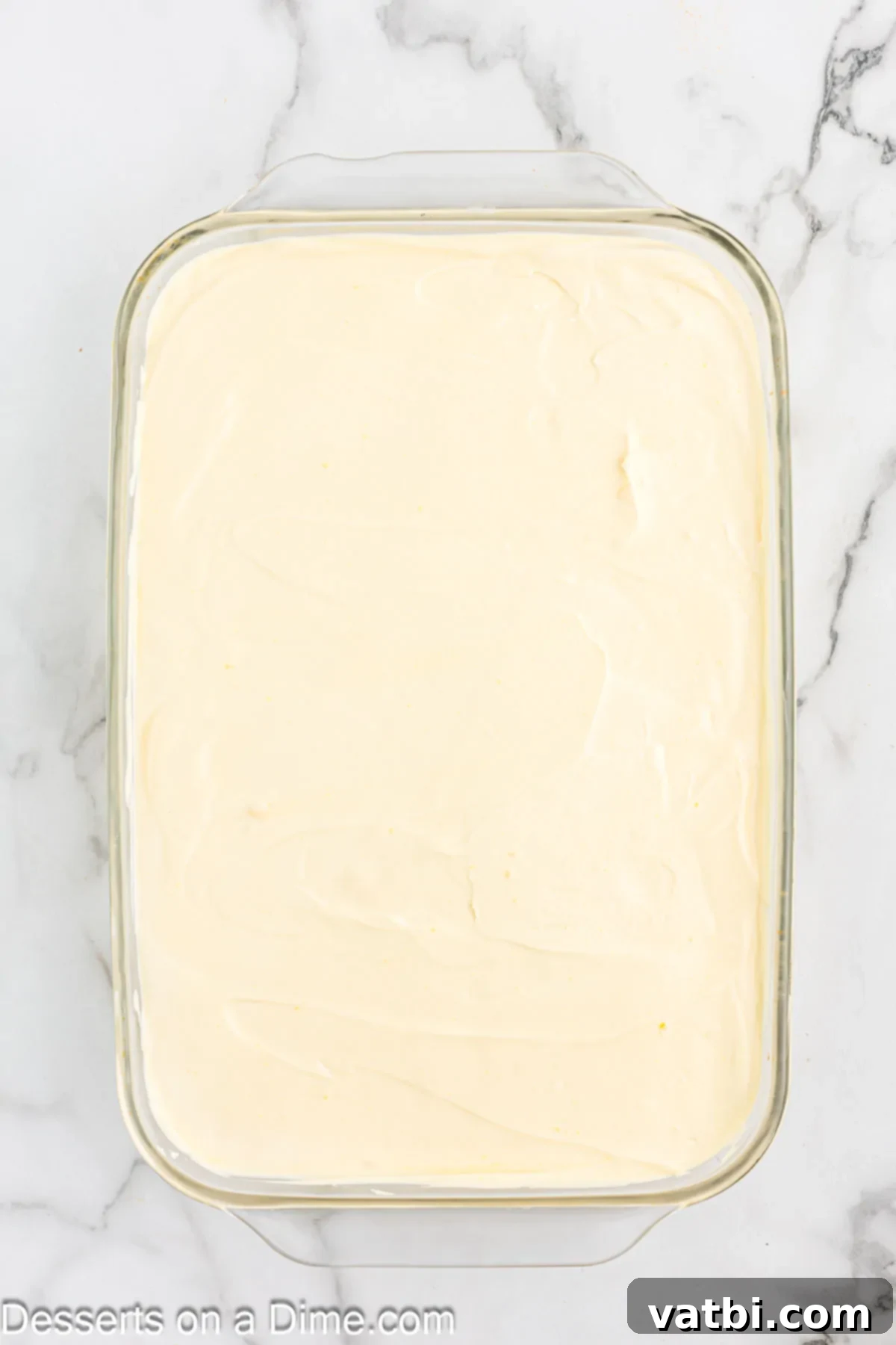 The combined pudding mixture being spread evenly over the sliced bananas in the baking pan.
