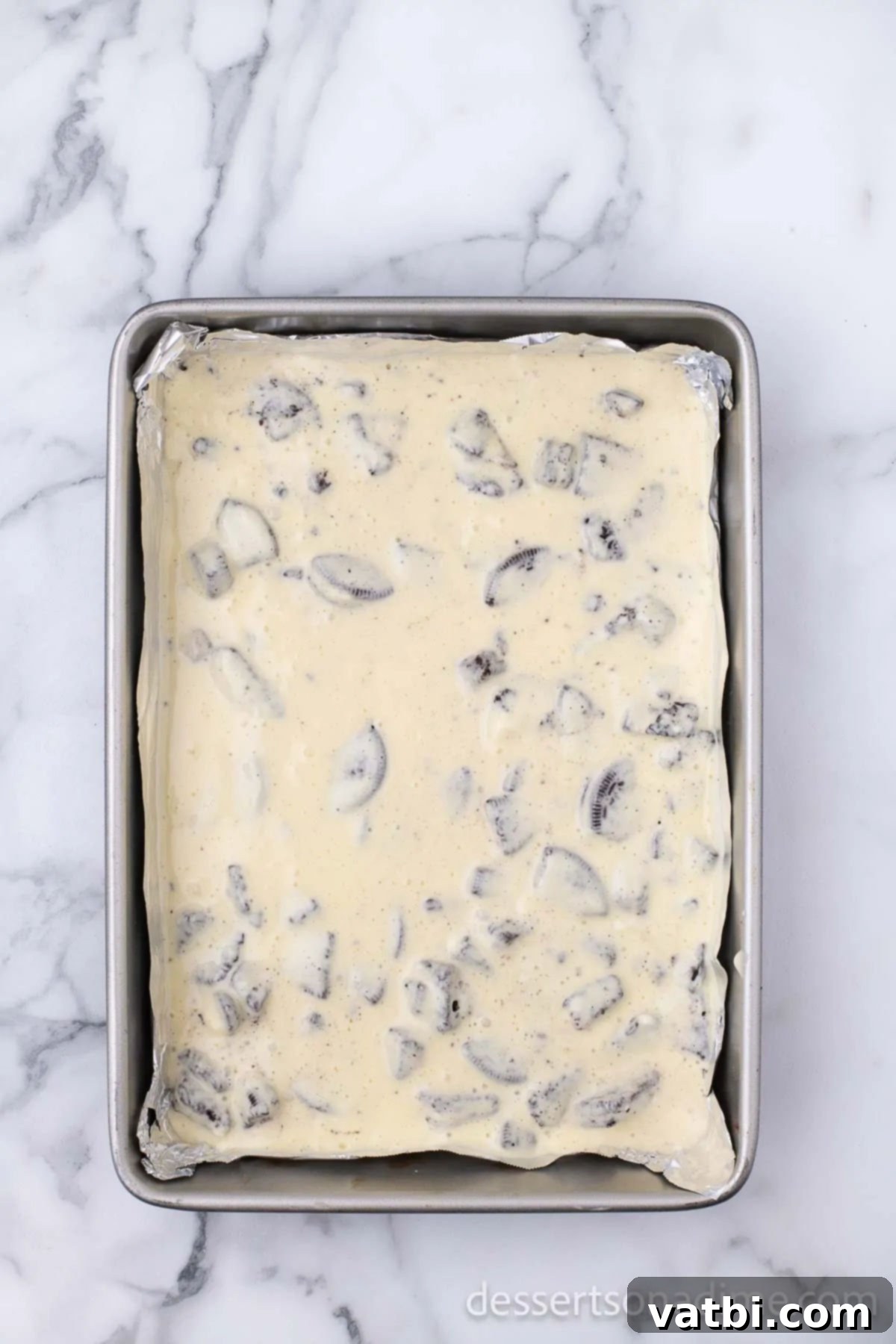 Irresistible Oreo Cheesecake Delight 12 The creamy cheesecake mixture being poured over the baked Oreo crust in the prepared pan.