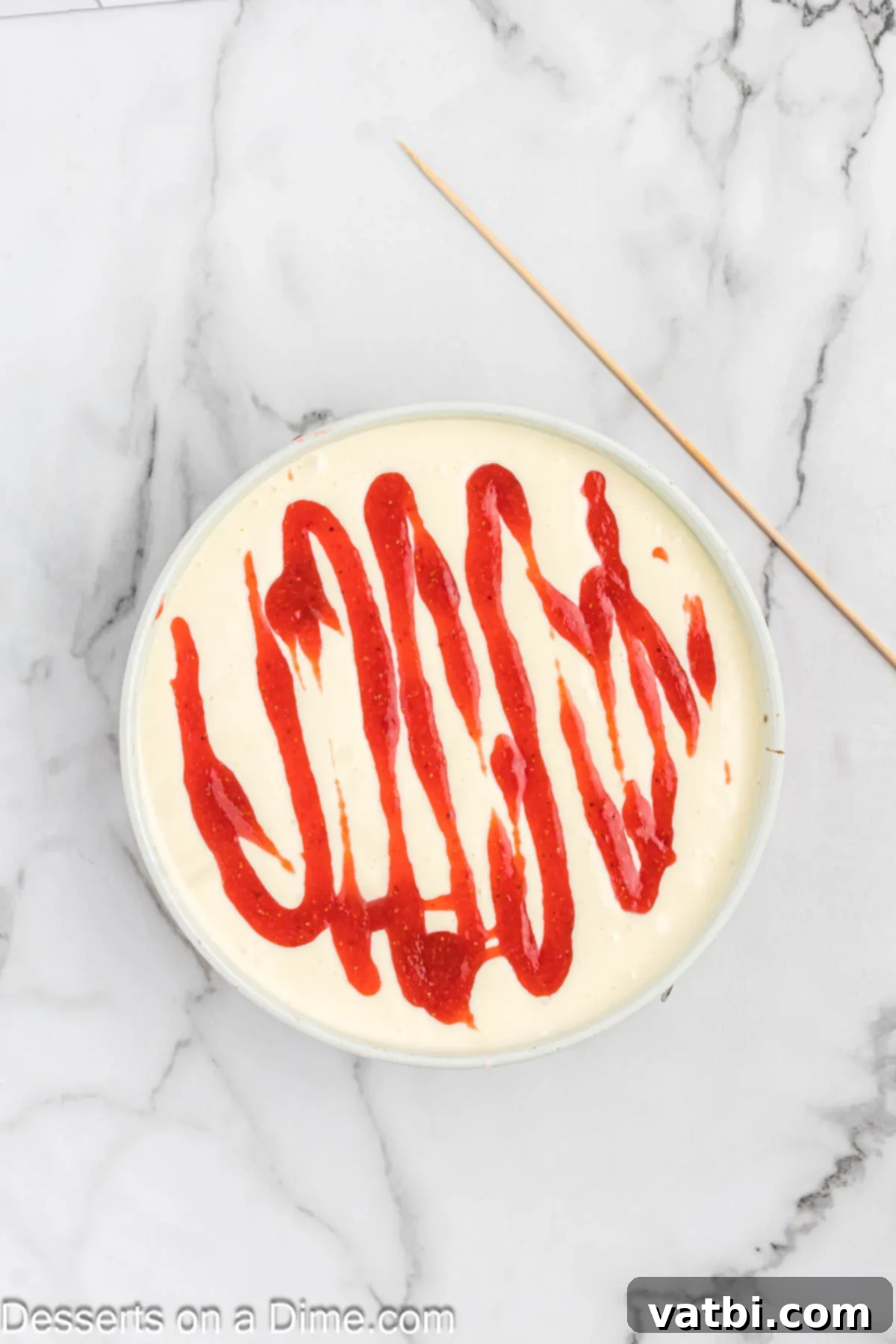 Strawberry sauce swirled on top of the creamy cheesecake batter.
