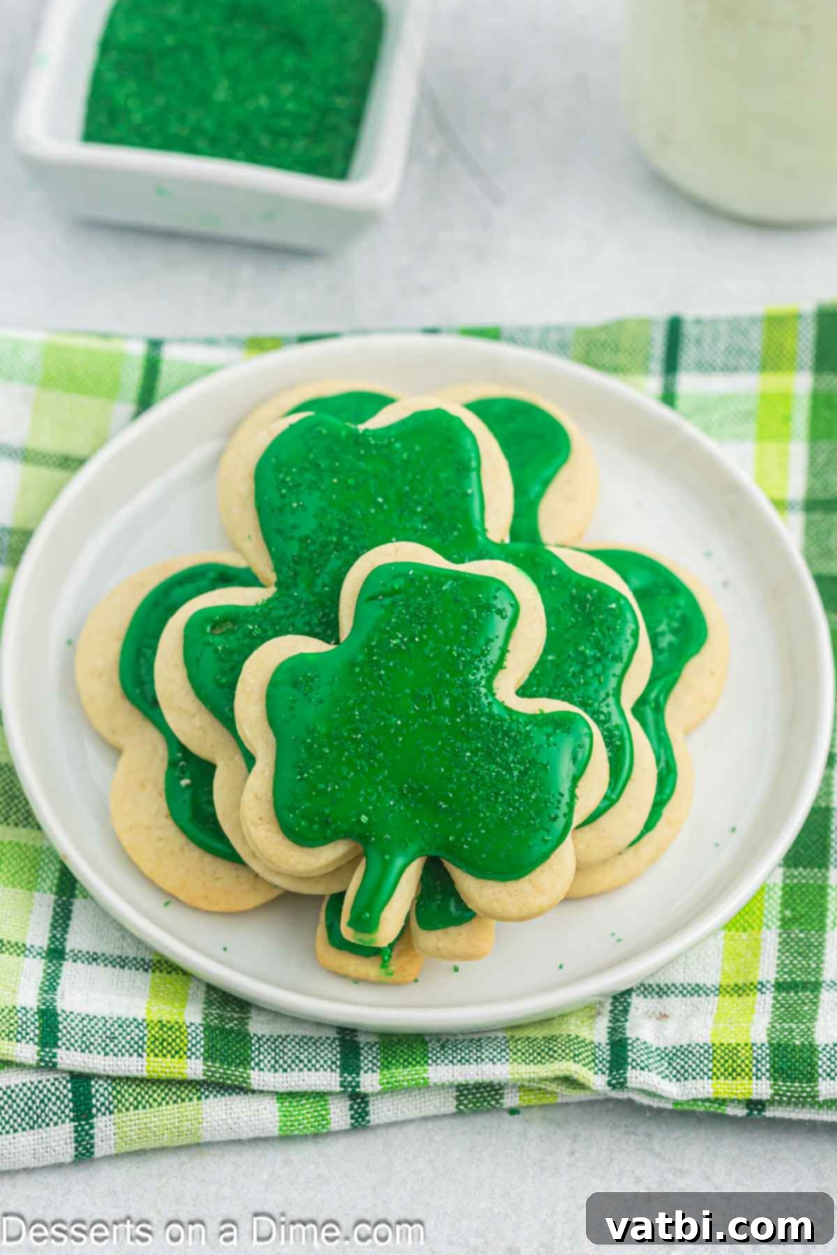 Sweet Clover Delights 2 A charming plate filled with beautifully decorated shamrock sugar cookies, topped with bright green frosting and festive sprinkles, ready for St. Patrick's Day celebration.