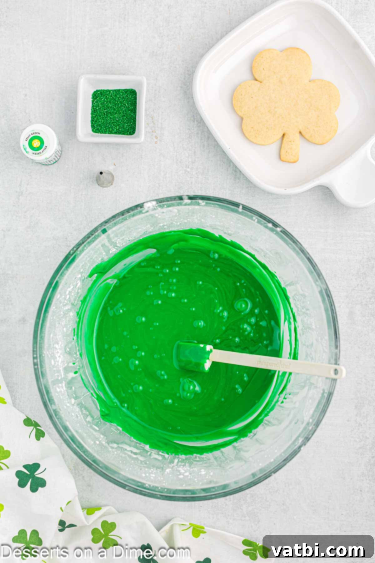 Sweet Clover Delights 12 Vibrant green gel food coloring being added to the white frosting in a mixing bowl, to create the signature St. Patrick's Day hue.